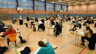 29.01.2021, Sachsen, Leipzig: In der Turnhalle vom Montessori-Schulzentrum in Leipzig schreiben 72 Schülerinnen und Schüler der Jahrgangsstufe 12 des Gymnasiums ihre Vorprüfungs-Klausur in den Leistungskursen Deutsch und Mathematik. Damit die Corona-Hygienebestimmungen eingehalten werden, wird die Halle regelmäßig gelüftet und die Tische haben einen Abstand bis zu drei Metern. Die Vorabitur-Klausur mit einer Prüfungslänge von 5,5 Stunden gilt als wichtiger Test für die im Frühjahr folgenden Abiturprüfungen. Wegen der schwierigen Lernbedingungen in der Pandemiezeit wurde die Prüfungszeit dabei um eine halbe Stunde verlängert. Foto: Waltraud Grubitzsch/dpa-Zentralbild/dpa - ACHTUNG: Nur zur redaktionellen Verwendung im Zusammenhang mit der aktuellen Berichterstattung, Verwendung nur im vollen Format. +++ dpa-Bildfunk +++