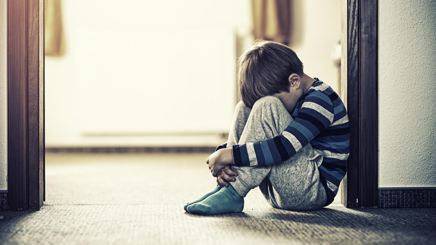 ein-deprimierter-kleine-junge-sitzt-auf-dem-boden