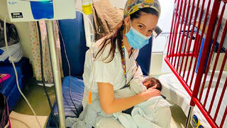 HANDOUT - 11.03.2021, ---, Jerusalem: Krankenschwester Jael Cohen stillt ein vier Monate altes Baby in der Hadassah-Klinik, nachdem die Mutter, eine Palästinenserin, bei einem Unfall schwer verletzt in das Jersualemer Krankenhaus gebracht worden war, und das Baby vor Hunger schrie und kein Fläschchen annehmen wollte. Die jüdische Krankenschwester hatte daraufhin das Kind an die Brust gelegt und gestillt, nachdem sie die Tante des Babys zuvor um Erlaubnis gebeten hatte. «Ich habe sofort gesehen, wie hungrig die Kleine war», erzählte die Krankenschwester Jael Cohen, die selbst ein einjähriges Kleinkind hat. Foto: Dovrut Hadassah/Hadassah-Klinik/dpa - ACHTUNG: Nur zur redaktionellen Verwendung im Zusammenhang mit der aktuellen Berichterstattung und nur mit vollständiger Nennung des vorstehenden Credits +++ dpa-Bildfunk +++