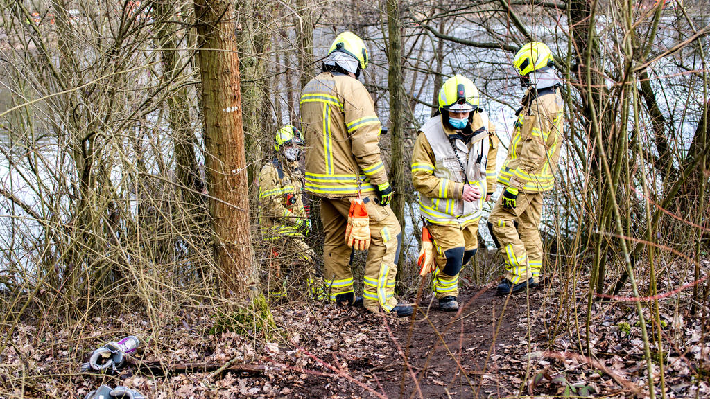 14.03.2021, Niedersachsen, Hannover: Einsatzkräfte der Feuerwehr stehen am Laher Teich, einem Baggersee im Nordosten der Stadt. Zwei Jungen im Alter von acht und neun Jahren waren in dem Gewässer ertrunken, nachdem sie einen ins Wasser gefallenen Bal