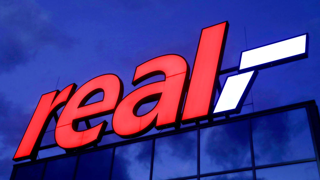 ARCHIV - 17.01.2020, Nordrhein-Westfalen, Köln: Das Logo leuchtet am Morgen auf dem Dach eines Real Warenhauses. (Zu dpa "Kartellamt gibt Edeka grünes Licht für Übernahme von 51 Real-Märkten ") Foto: Oliver Berg/dpa +++ dpa-Bildfunk +++