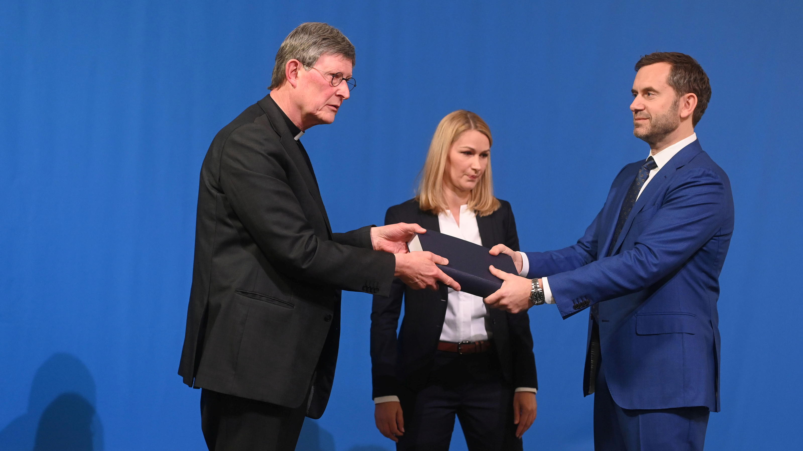 Lawyer Kerstin Stirner (C) looks on as Bjoern Gercke (R), an attorney mandated by the Church, hands over to Cologne's archbishop Rainer Maria Woelki a report on abuse by clergy during a news conference, in Cologne, Germany March 18, 2021.  Ina Fassbe