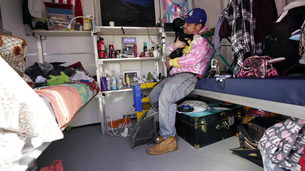 John Golka hugs his dog Smalls inside a tiny home, Thursday, Feb. 25, 2021, in the North Hollywood section of Los Angeles. (AP Photo/Marcio Jose Sanchez)