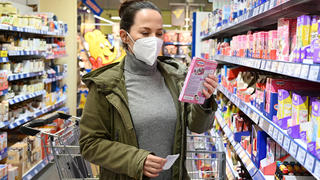 Eine Frau mit Mund Nasenschutz Maske vom Typ FFP2 beim Einkaufen.