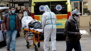 11.03.2021, Griechenland, Athen: Medizinische Mitarbeiter in Schutzausrüstung transportieren einen Patienten auf einer Trage, um ihn in einem Krankenhaus in Athen zu verlegen. Foto: Marios Lolos/Xinhua/dpa +++ dpa-Bildfunk +++