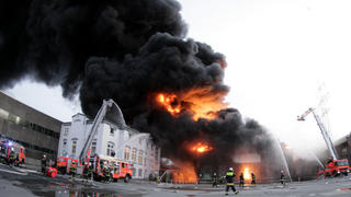 Feuerwehrleute stehen am Montag (02.01.2012) in Hamburg vor einer brennenden Lagerhalle. Am Mittag war das Feuer in einer Lagerhalle, in der Gabelstapler, Kautschuk und Heizöl gelagert wurden, ausgebrochen. Foto: Daniel Bockwoldt dpa/lno (zu lno vom 02.01.2012)  +++(c) dpa - Bildfunk+++