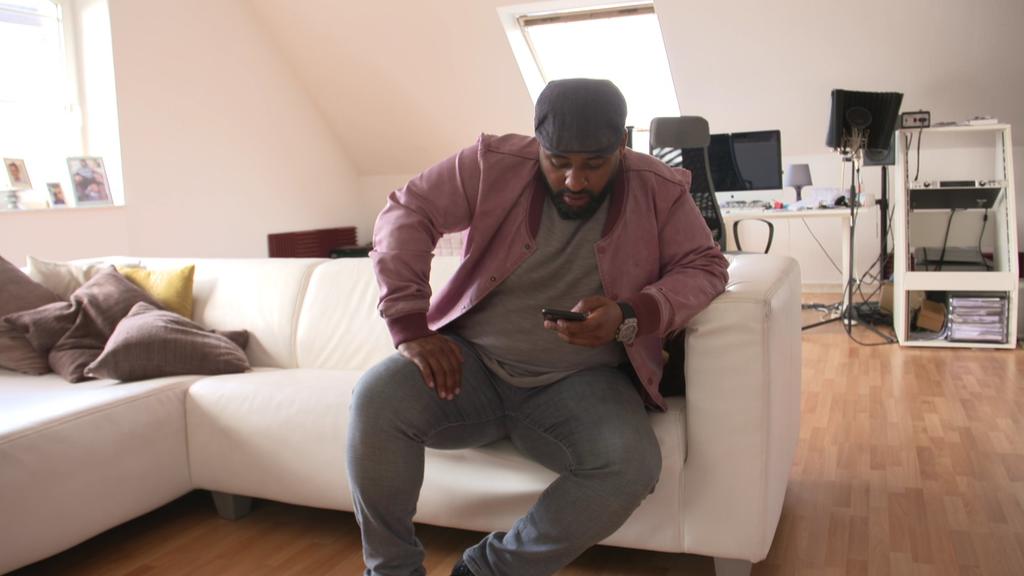 Ado Kojo schaut sich Reaktionen auf seinem Smartphone an