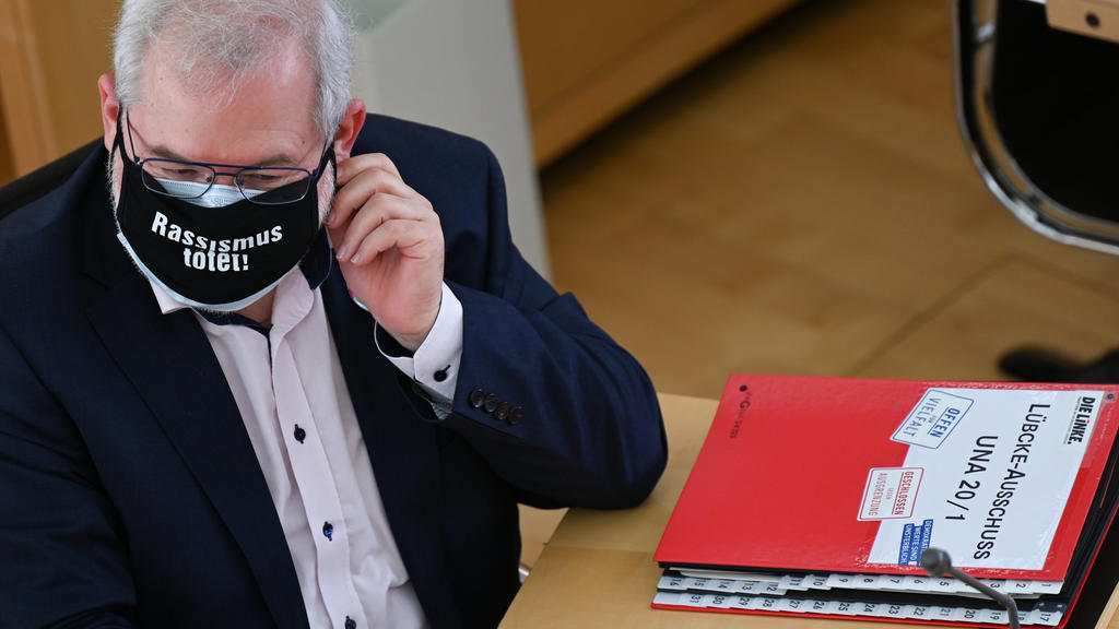 31.03.2021, Hessen, Wiesbaden: Vor dem Abgeordneten Hermann Schaus (Die Linke), der eine schwarze Maske mit der Aufschrift "Rassismus tötet" trägt, liegt zu Beginn der Sitzung des Lübcke-Untersuchungsausschusses im hessischen Landtag ein Aktenordner