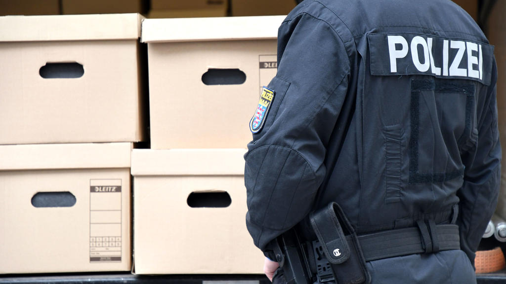 ARCHIV - 20.01.2021, Hessen, Wiesbaden: Ein Polizeibeamter steht vor einem Lastwagen, der mit Kisten mit Aktenordnern beladen ist. Der Untersuchungsausschuss des hessischen Landtages zum Mordfall Lübcke hat wichtige Akten geliefert bekommen. (zu dpa