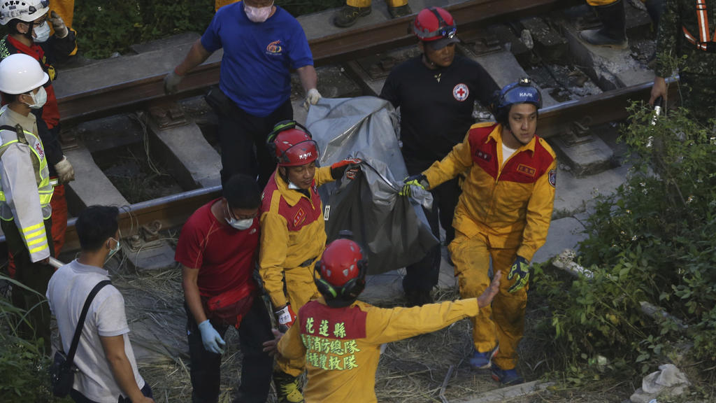 Rescue workers recover a body from a derailed train near the Taroko Gorge area in Hualien, Taiwan on Friday, April 2, 2021. The train partially derailed in eastern Taiwan on Friday after colliding with an unmanned vehicle that had rolled down a hill,