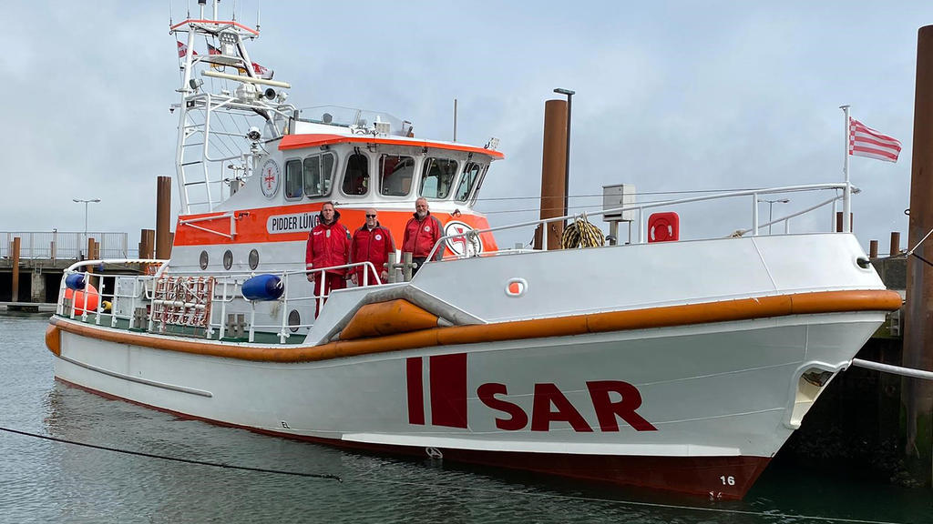 04.04.2021, Dänemark, Havneby: Seenotretter Christopher Kölln (l-r), Holger Speck und Gerhard Reinfeld freuen sich am Ostersonntag an Bord des Seenotrettungskreuzers «Pidder Lüng», dass die junge Mutter Lara Müller-Maron und ihr Baby Bosse nach der G