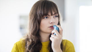  Female breathing through asthma inhaler while looking away model released Symbolfoto property released SGF02750