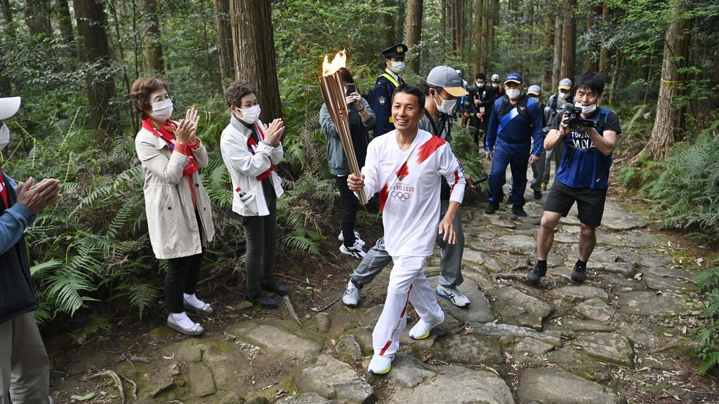 08.04.2021, Japan, Kihoku: Ein Mann läuft mit der Fackel beim Olympischen Fackellauf auf einem Bergpfad in der Präfektur Mie. Foto: --/kyodo/dpa +++ dpa-Bildfunk +++