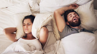 Mann schnarcht im Bett neben Partnerin