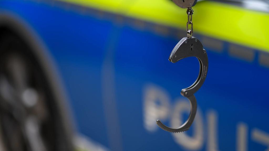 Handschellen vor einem Streifenwagen