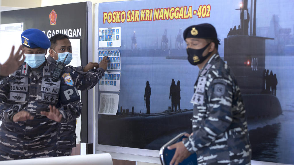 Tiga personel militer Indonesia berbicara di depan foto-foto kapal selam Indonesia tentang kemungkinan lokasi.