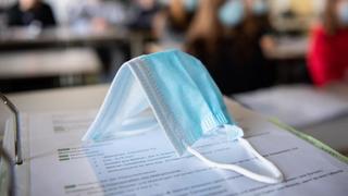 Ein Mund-Nasen-Schutz liegt im Unterricht auf Unterlagen