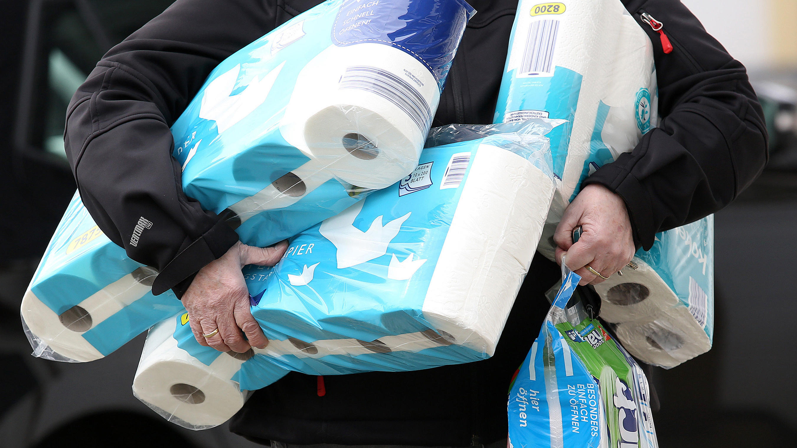 ARCHIV - 18.03.2020, Nordrhein-Westfalen, Siegen: Ein Mann trägt eingekauftes Toilettenpapier und Küchenrollen aus einem Supermarkt. (zu dpa «Spätfolgen der Hamsterkäufe: Papierbranche verkauft weniger Klopapier») Foto: Rene Traut/dpa +++ dpa-Bildfun