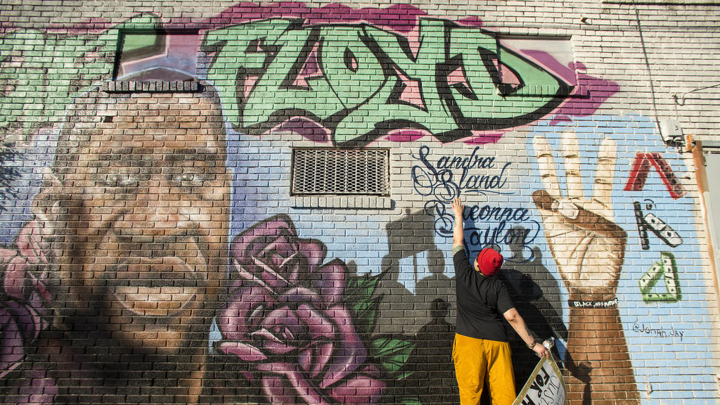 Daryel Simmons reaches up to touch the names of Sandra Bland and Breonna Taylor as she came to a George Floyd memorial mural after learning of the guilty verdict on all counts in the murder trial of former Minneapolis Officer Derek Chauvin in the dea