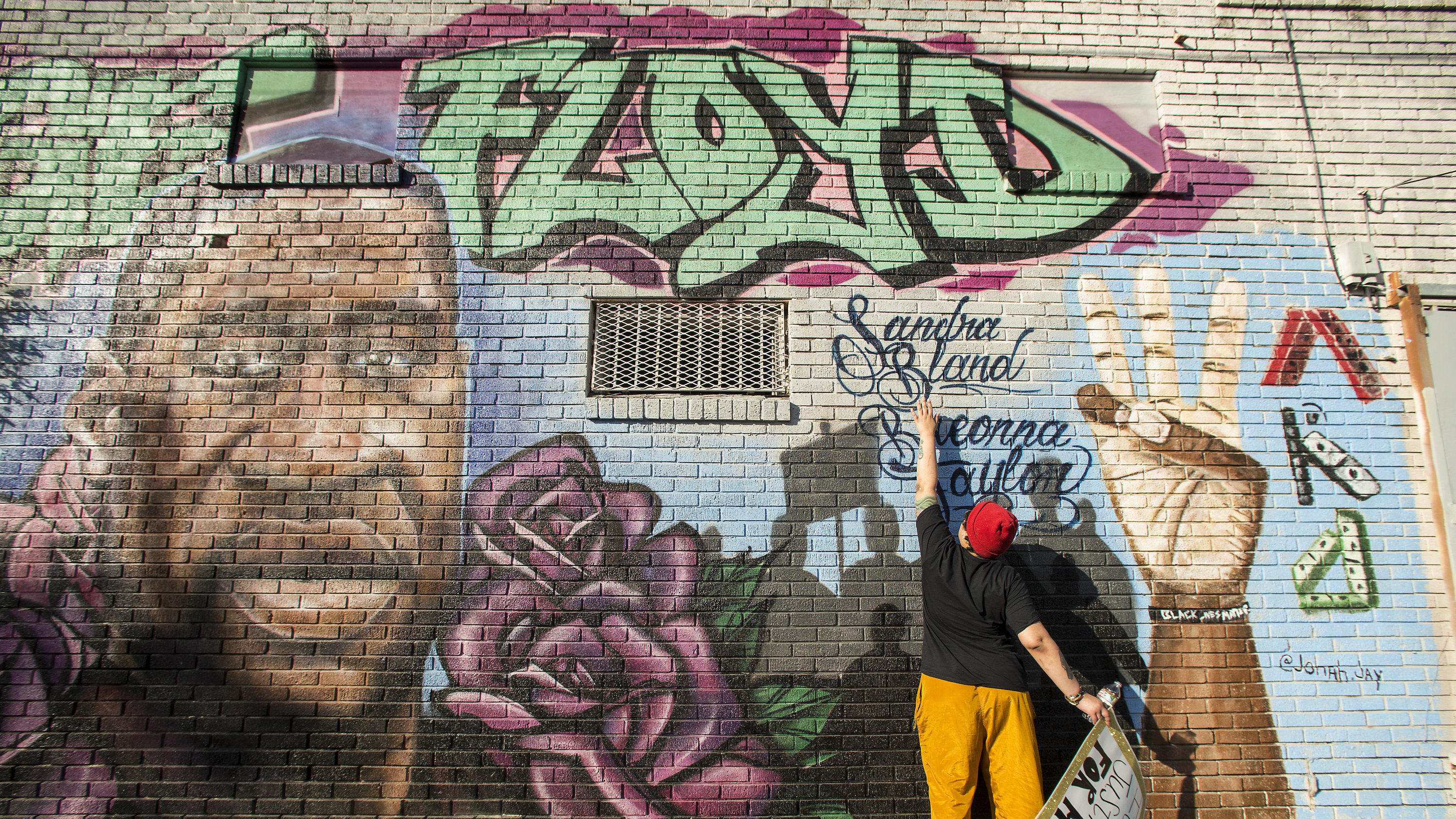 Daryel Simmons reaches up to touch the names of Sandra Bland and Breonna Taylor as she came to a George Floyd memorial mural after learning of the guilty verdict on all counts in the murder trial of former Minneapolis Officer Derek Chauvin in the dea