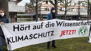29.04.2021, Baden-Württemberg, Karlsruhe: Mitglieder der Karlsruher Gruppe von Fridays for Future halten vor dem Bundesverfassungsgericht ein Transparent auf dem steht ·Hört auf die Wissenschaft! Klimaschutz jetzt!·. Das Gericht verkündete sein Urteil zum Klimaschutzgesetz. Laut dem Urteil reicht das Klimaschutzgesetz nicht weit genug. Die Richter verpflichteten den Gesetzgeber am Donnerstag, bis Ende kommenden Jahres die Reduktionsziele für Treibhausgasemissionen für die Zeit nach 2030 näher zu regeln. Foto: Uli Deck/dpa +++ dpa-Bildfunk +++
