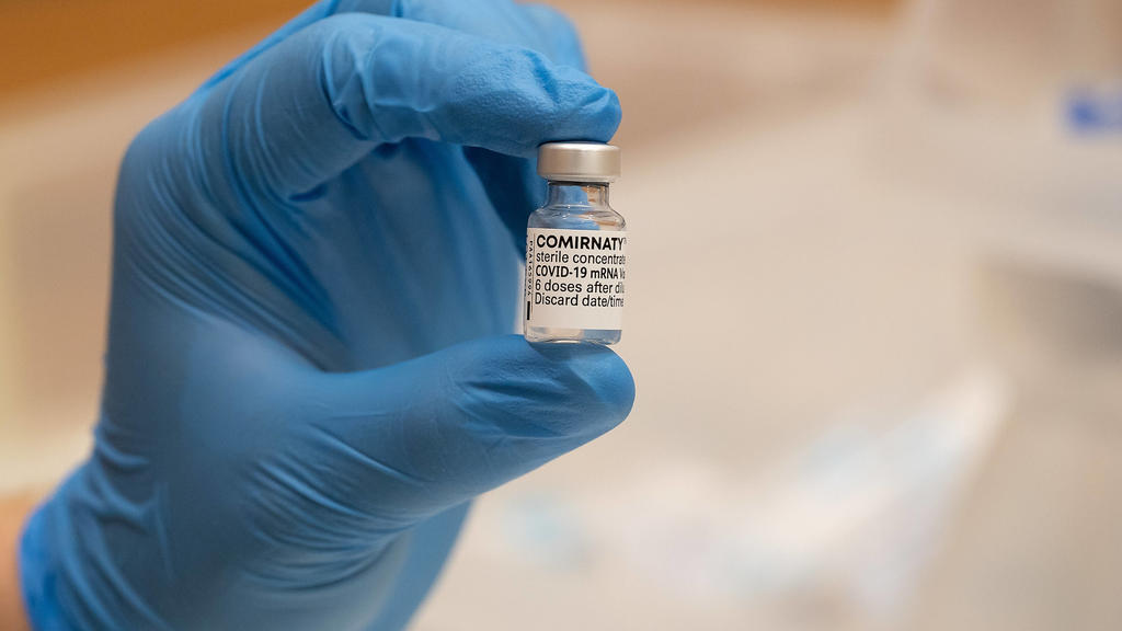Osnabrück, Deutschland 29. April 2021: Eine Hand mit blauen Sicherheitshandschuhen hält eine Ampulle mit dem Impfstoff Comirnaty BNT162b2, Biontech / Pfizer zur Impfung gegen das Coronavirus. Impfzentrum Schlosswallhalle Niedersachsen *** Osnabrück,