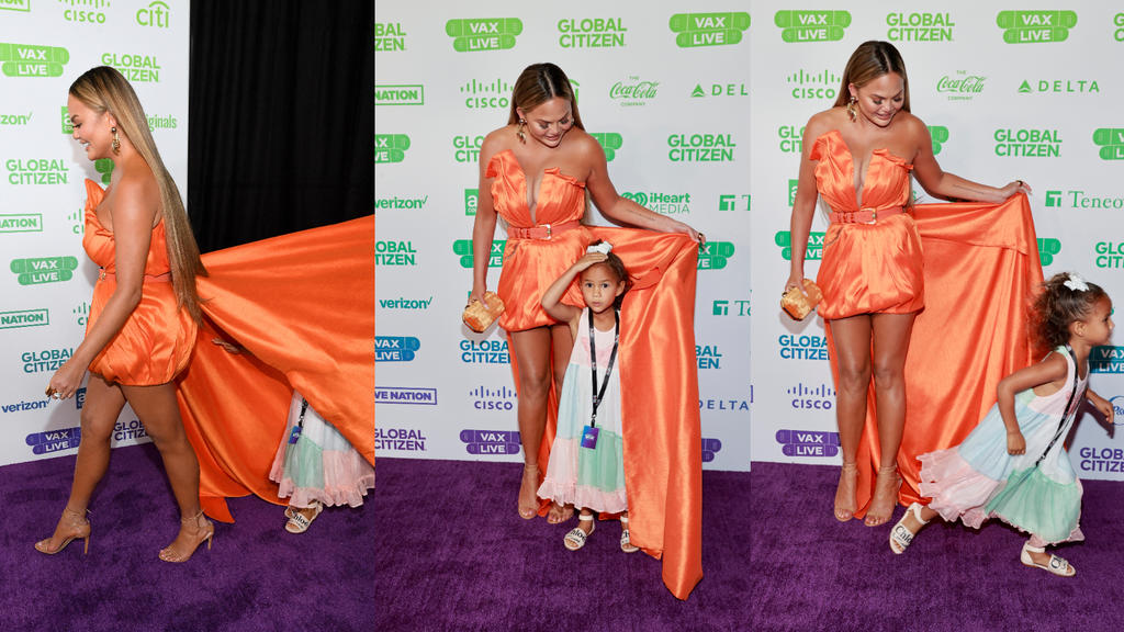 Chrissy Teigens Tochter Luna versteckt sich auf dem roten Teppich unter Mamas Kleid.
