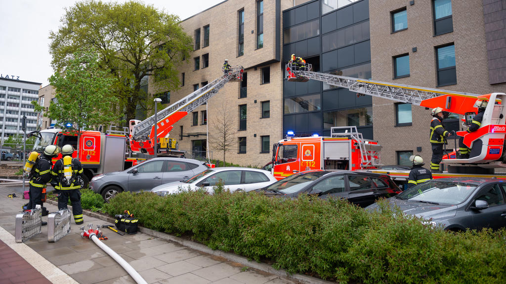 ARCHIV - 01.05.2020, Hamburg: Zwei Drehleitern und mehrere Einsatzfahrzeuge stehen vor einem Wohnhaus. Weil er seine Ex-Frau mit einem Messer angegriffen und sie sowie einen Sohn mit Benzin übergossen und angezündet haben soll, muss sich ein 50-Jähri