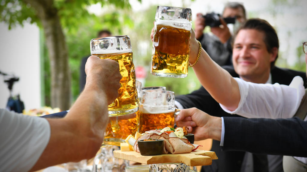 Drei Menschen stoßen mit Bierkrügen an.