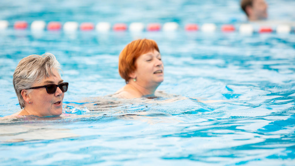 Zwei Frauen schwimmen in einem Becken.