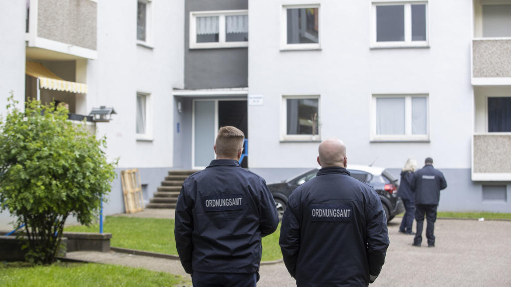 18.05.2021, Nordrhein-Westfalen, Velbert: Mitarbeiter des Ordnungsamt stehen vor einem Eingang eines Hochhauses. Bereits seit Sonntag sind fast 200 Personen aus zwei Hochhäusern unter Quarantäne gestellt. Im Fall der rund 200 Menschen unter Quarantän