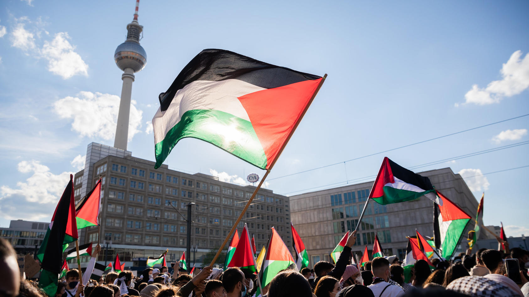 19.05.2021, Berlin: Teilnehmer einer Demonstration unter dem Motto «Gegen die israelische Aggression in Palästina» haben sich mit Fahnen auf dem Alexanderplatz versammelt. Foto: Christoph Soeder/dpa +++ dpa-Bildfunk +++