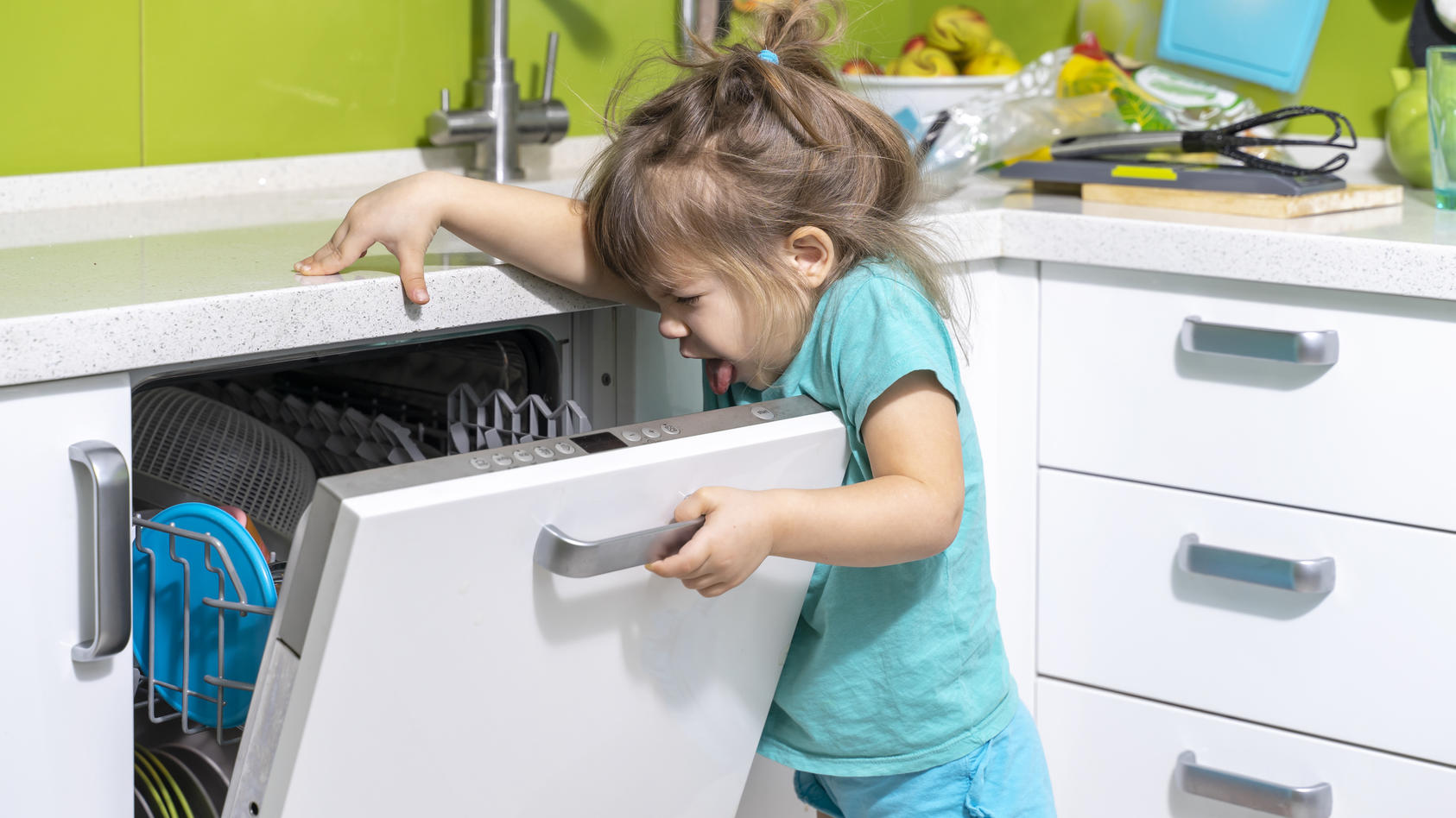 Ein kleines Mädchen öffnet die Spülmaschine und ekelt sich vor dem Geruch.