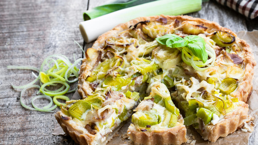 Eine Quiche gefüllt mit Lauch, ansprechend aussehend angerichtet.