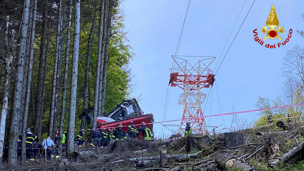 HANDOUT - 23.05.2021, Italien, Stresa: Die Aufnahme der Feuerwehr zeigt Feuerwehrleute an einer abgestürzten Gondel, die in einem Waldstück liegt. Bei dem Seilbahnunglück in der norditalienischen Provinz Verbano-Cusio-Ossola sind neun Menschen ums Le