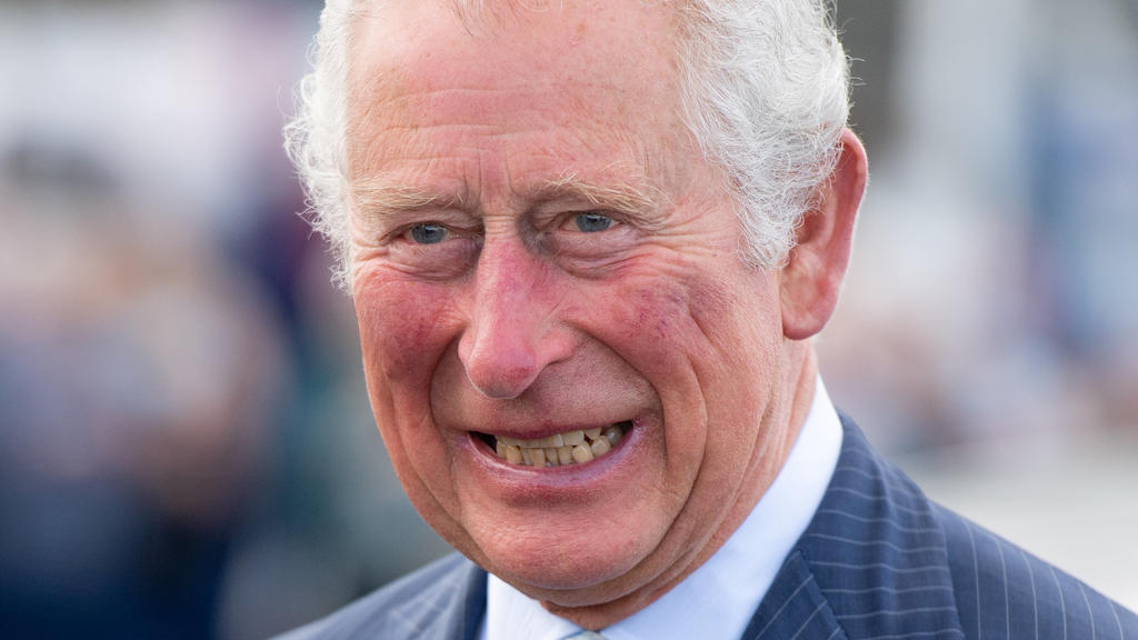 19.05.2021, Großbritannien, Donaghadee: Der britische Prinz Charles, Prinz von Wales, lacht bei einem Besuch im Hafen von Donaghadee, wo er Steine besichtigte, die die Hafenmauern säumen und während der Pandemie von den Menschen vor Ort mit Botschaft