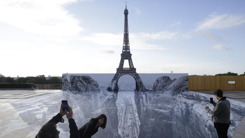 19.05.2021, Frankreich, Paris: Menschen fotografieren Kunstwerke des französischen Fotografen und Streetart-Künstlers JR, die auf dem Trocadero-Platz vor dem Eiffelturm ausgestellt sind. Foto: Thibault Camus/AP/dpa - ACHTUNG: Nur zur redaktionellen V