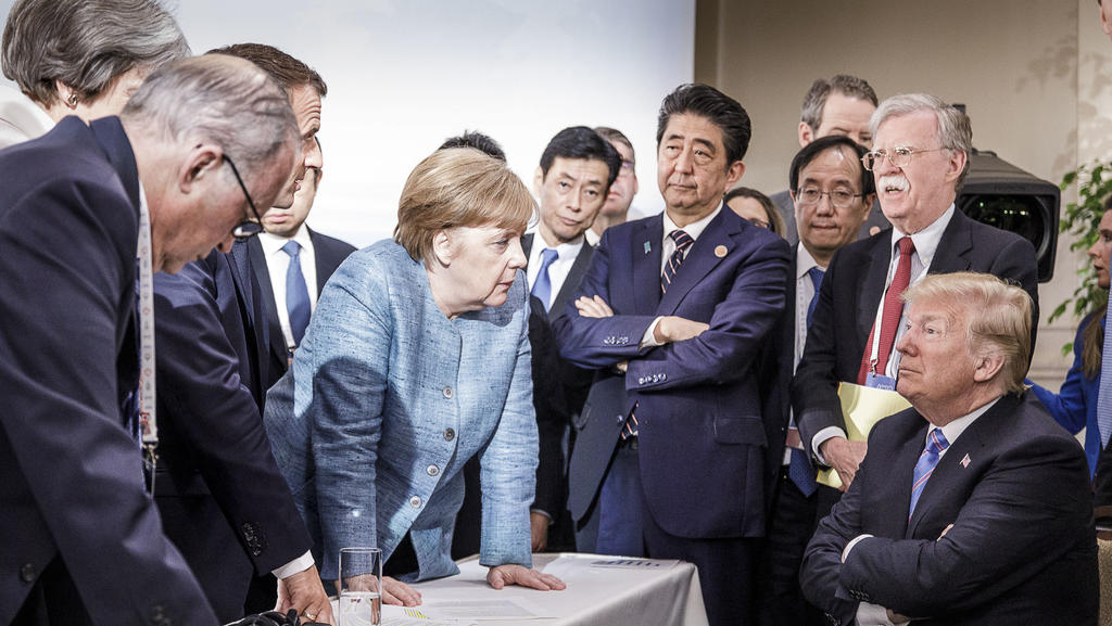 HANDOUT - 09.06.2018, Charlevoix, La Malbaie, Quebec, Kanada: Bundeskanzlerin Angela Merkel (CDU, M) spricht mit US-Präsident Donald Trump (r) während der Beratungen am Rande der offiziellen Tagesordnung. Emmanuel Macron (2.v.l), Präsident von Frankr