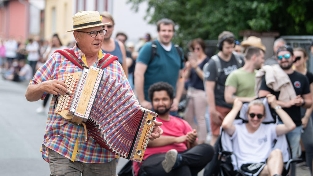 12.06.2021, Hessen, Babenhausen: Mit einer spontanen musikalischen Einlage unterhält Harmonika-Spieler Norbert Herbert - Künstlername ·Happy-Man· - Impfwillige, die in einer mehrer hundert Meter langen Schlange vor einer Arztpraxis auf ihre Corona-Sc