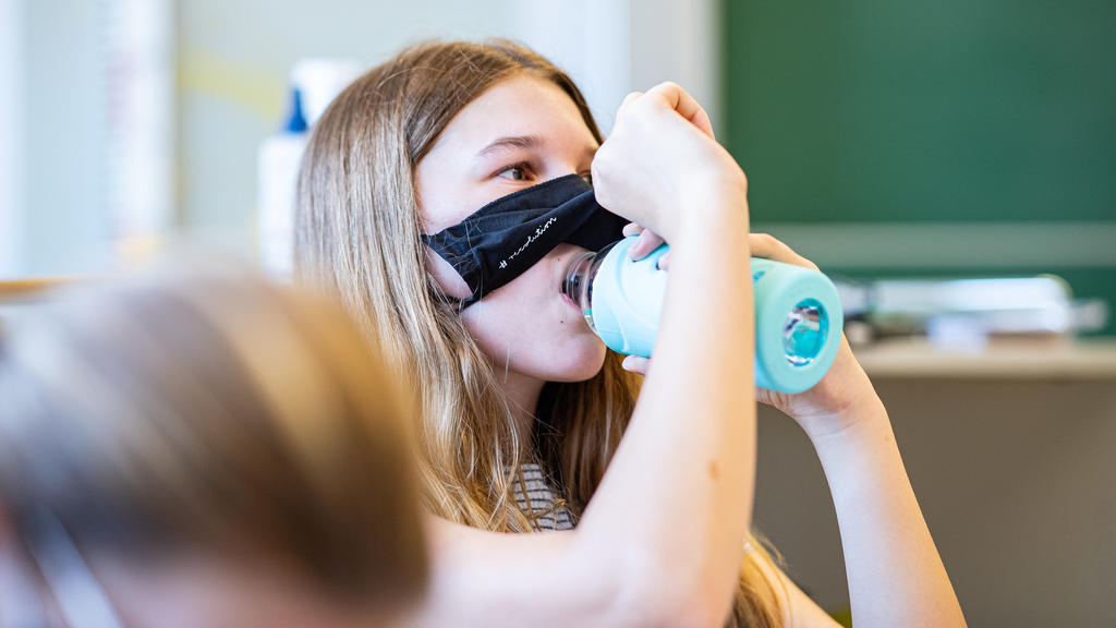 12.08.2020, Nordrhein-Westfalen, Münster: Eine Schülerin der Klasse 8a der Gesamtschule in Münster, hebt ihre Mund- und Nasenmaske an um etwas zu trinken. Das Bundesland Nordrhein-Westfalen startet mit Maskenpflicht nach den Sommerferien wieder in de