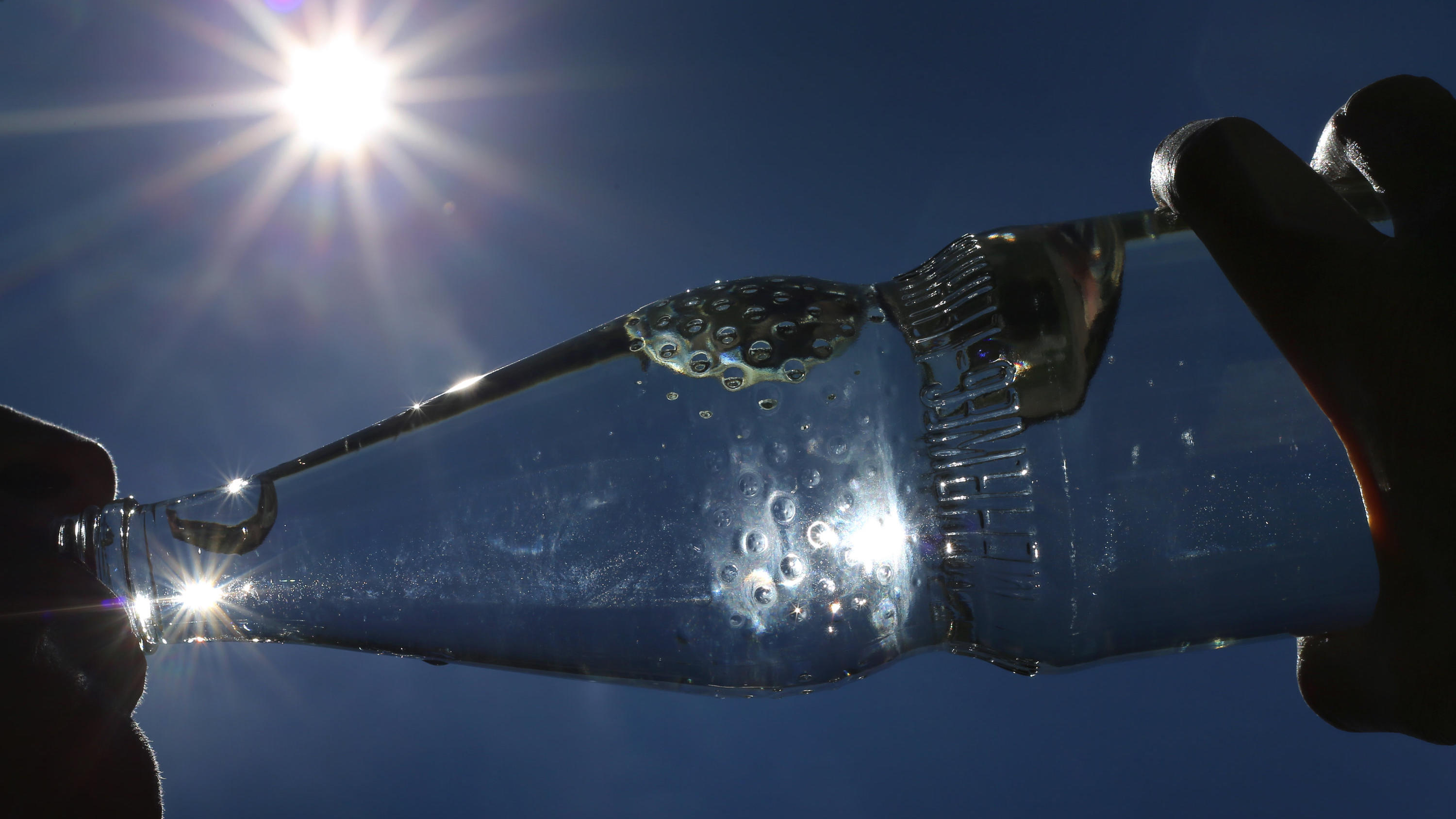 Eine Frau trinkt im Sonnenschein aus einer Flasche sprudelndes Mineralwasser. Draußen ist es richtig heiß - ein kaltes Getränk muss her. Aber ist das eigentlich eine gute Idee? (zu dpa: "Sommer-Fakten gecheckt: Z