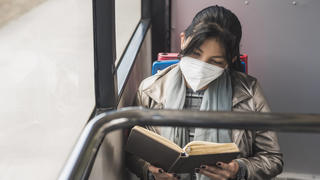  Woman wearing protective mask while reading book in bus model released Symbolfoto DSIF00076