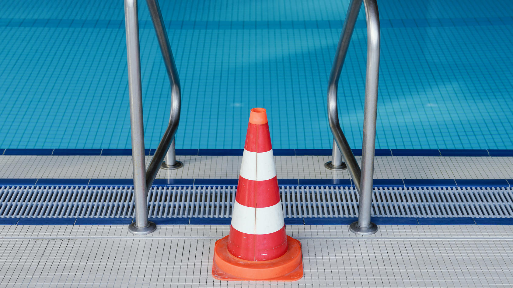 ARCHIV - 16.03.2020, Baden-Württemberg, Heidelberg: Eine Pylone steht im Hallenbad Köpfel an einer Leiter des Schwimmerbeckens. Das Schwimmbad ist wegen der Coronakrise bis auf weiteres geschlossen. (Zu dpa «Verband: Hallenbäder im Sommer für Anfänge