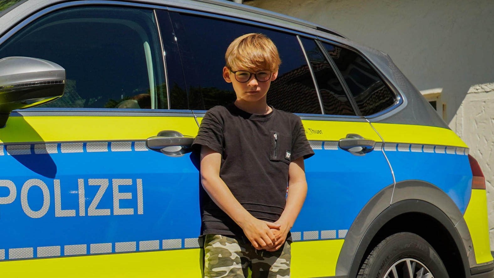 Lennard steht vor einem Polizeiauto