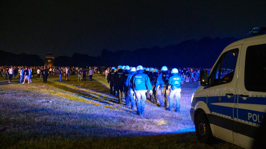 18.06.2021, Hamburg: Behelmte Polizisten laufen begleitet von einem Mannschaftswagen in Richtung der Menschen auf der Stadtpark-Wiese. Die Polizei hat eine Party mit rund 3000 Menschen im Hamburger Stadtpark aufgelöst. (zu dpa: «Polizei räumt Party v