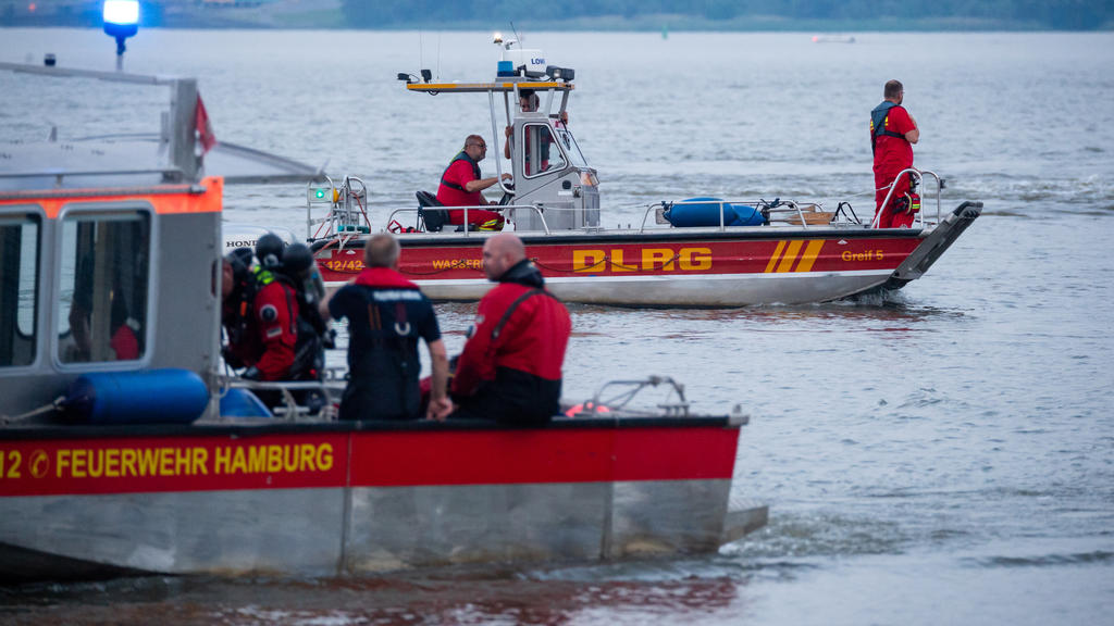18.06.2021, Hamburg: Kleinboote von DLRG und Feuerwehr fahren bei der Suche über die Elbe. Feuerwehr und Polizei haben am Abend zweieinhalb Stunden nach einem jungen Mann gesucht, der von einem Signalturm in die Elbe gesprungen und nicht mehr aufgeta