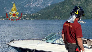 HANDOUT - 26.06.2021, Italien, Lenno: Ein Feuerwehrmann steht neben einem Motorboot, das auf dem Comer See mit einem anderen Motorboot zusammengestoßen war. Dabei sei nach Angaben der Polizei ein 22 Jahre alter Italiener ums Leben gekommen, zwei weitere wurden verletzt. Eine abschließende Unglücksursache gebe es noch nicht. Foto: Vigilii Del Fuoco/dpa - ACHTUNG: Nur zur redaktionellen Verwendung im Zusammenhang mit der aktuellen Berichterstattung und nur mit vollständiger Nennung des vorstehenden Credits +++ dpa-Bildfunk +++