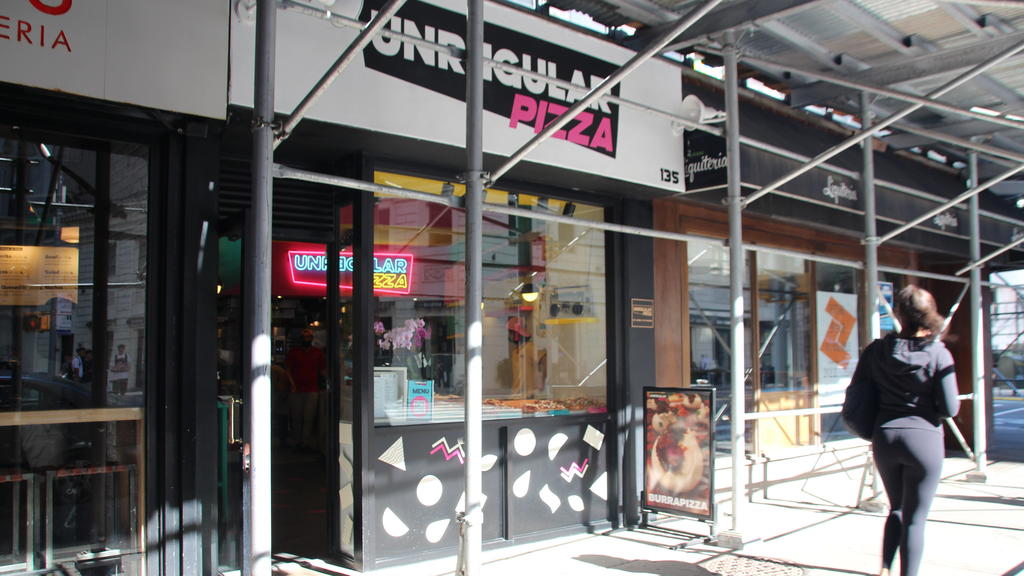 Eine Frau geht an Lamonaca Pizzeria "Unregular Pizza" vorbei.
