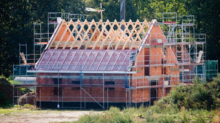 Ein Richtkranz weht am Dachstuhl eines neu gebauten Einfamilienhauses in einer Neubausiedlung in der Region Hannover.