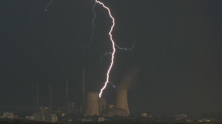 Ein Blitz zuckt hinter dem Kraftwerk Staudinger.